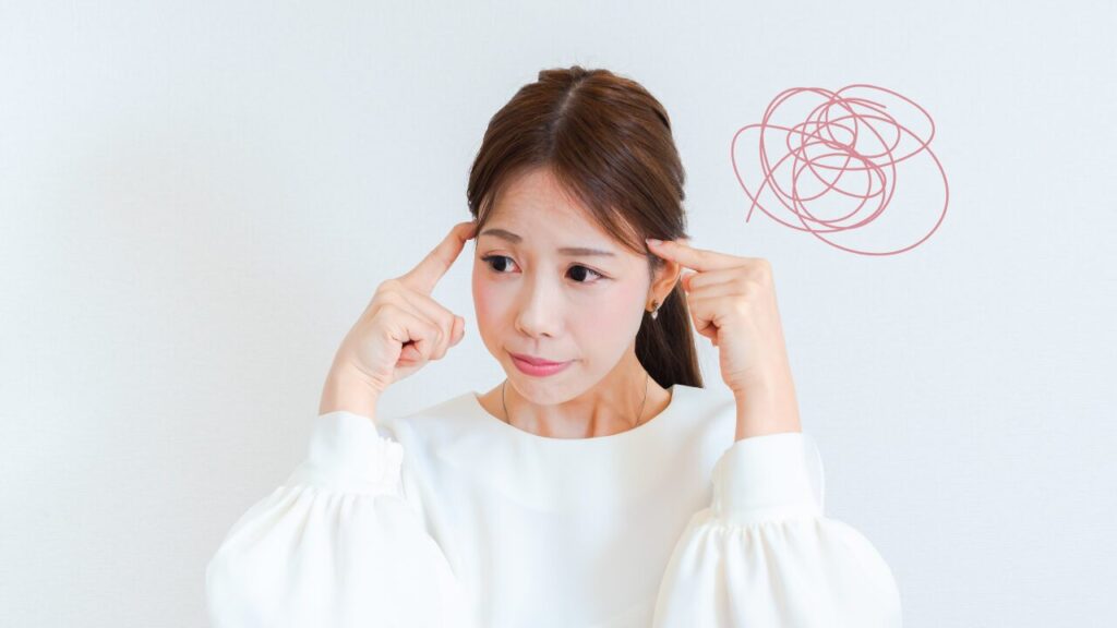 女性が頭に人差し指を当てて悩んでいる様子。