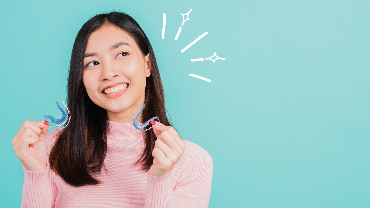矯正用マウスピースを手に笑顔の女性の画像