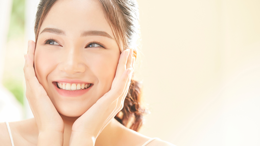 両手を頬にあてている笑顔の女性。