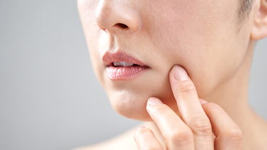 ほうれい線をのばすように手をあてている女性の口元