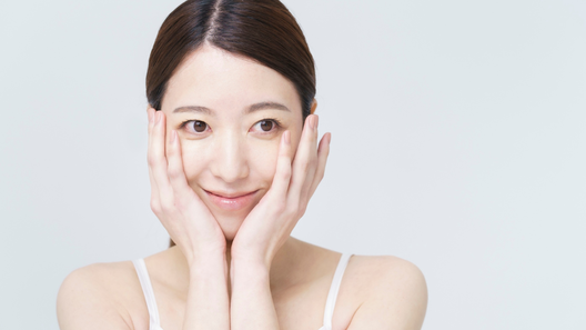 両手を頬にあてて笑う若々しい女性。