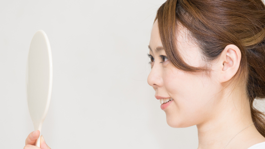 手鏡を見る笑顔の女性。